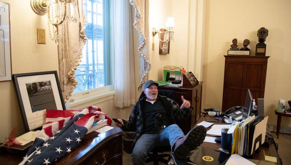 En esta foto de archivo tomada el 6 de enero de 2021, Richard Barnett, un partidario de Donald Trump, se sienta dentro de la oficina de la presidenta de la Cámara de Representantes Nancy Pelosi. (SAUL LOEB / AFP).