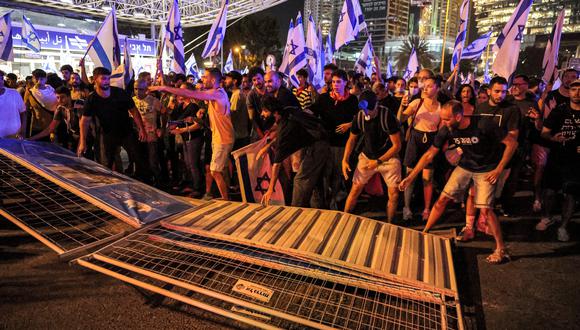 Los manifestantes derriban una barrera de la policía antidisturbios durante una manifestación de protesta contra el plan de reforma judicial del gobierno israelí en Tel Aviv el 24 de julio de 2023. (Foto de JACK GUEZ / AFP)