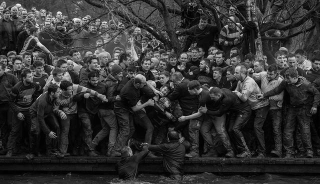 (FILES) In this file photo taken on February 28, 2017 Competitors from the opposing teams, the Up'ards and the Down'ards, reach for the ball during the annual Royal Shrovetide Football Match in Ashbourne, northern England.  British AFP Photographer Oli Scarff was nominated on February 14, 2018 for the World Press Photo award in the Sport Singles category.  / AFP / Oli SCARFF