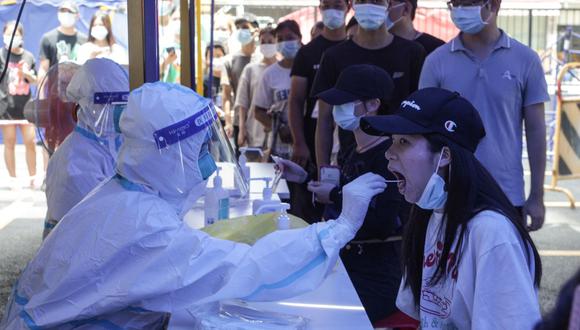 Esta foto tomada el 30 de mayo de 2021 muestra a una mujer (derecha) recibiendo una prueba de ácido nucleico para el coronavirus en Cantón, en la provincia de Guangdong, en el sur de China. (STR / AFP).