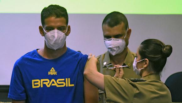 El atleta brasileño de arco y flecha Marcus Vinicius D'Almeida es inoculado con una vacuna contra el coronavirus COVID-19 como parte de un proyecto organizado por el gobierno federal brasileño para vacunar a ciudadanos brasileños acreditados en los Juegos Olímpicos de Tokio. (Foto de MAURO PIMENTEL / AFP).