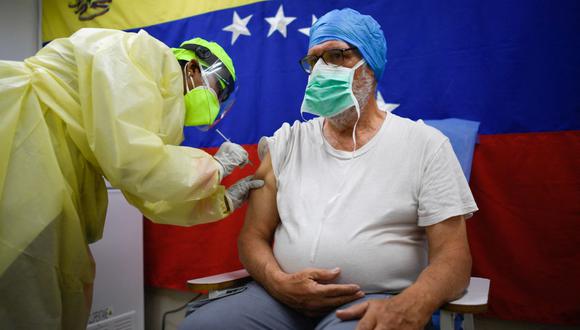 Un trabajador de la salud administra una dosis de la vacuna Sputnik V contra el COVID-19 a un miembro del personal del Hospital Pérez de León, en el barrio de Petare, en el este de Caracas (Venezuela), el 19 de febrero de 2021. (Federico PARRA / AFP)