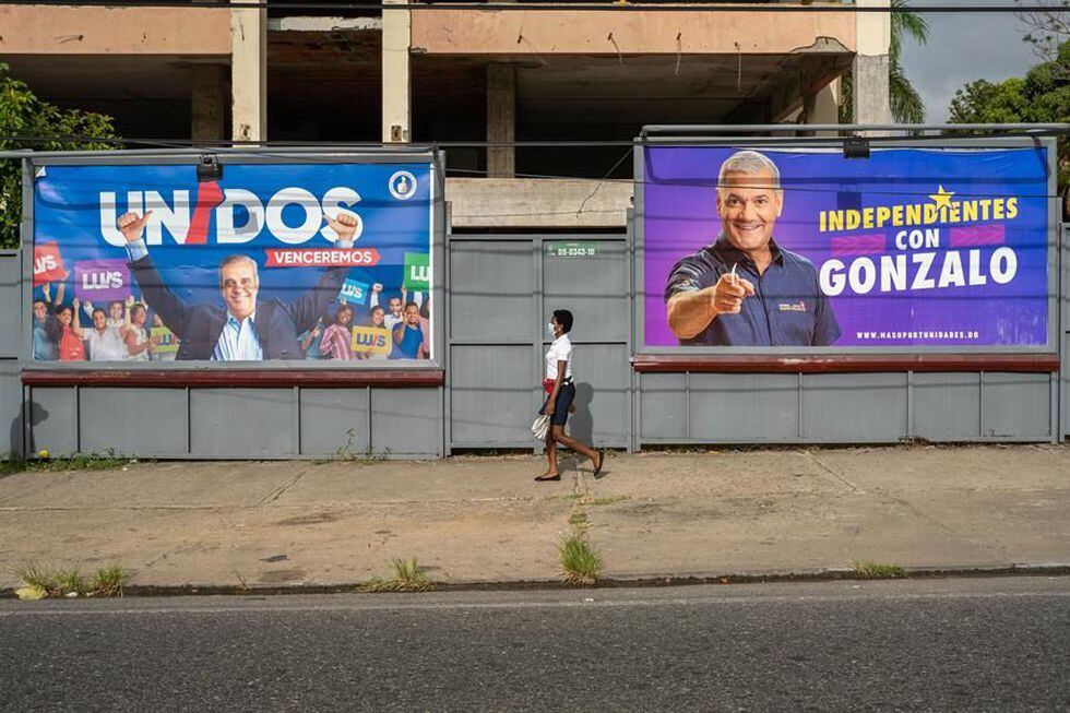 Una mujer con tapabocas camina cerca a vallas publicitarias de los candidatos presidenciales Luis Abinader y Gonzalo Castillo en Santo Domingo (República Dominicana). (EFE/ Francesco Spotorno).