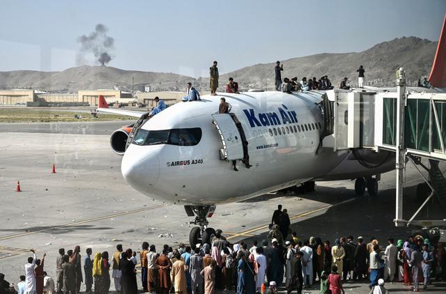 Los afganos se suben a un avión mientras esperan en el aeropuerto de Kabul el 16 de agosto de 2021 para escapar de los talibanes, que tomaron el control de Afganistán. (Wakil Kohsar / AFP).