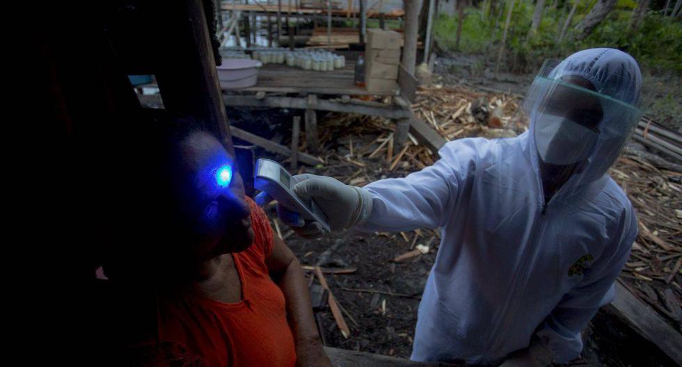 Trabajador de salud inspecciona a una persona con síntomas de COVID-19 en una comunidad de la selva brasilera.  (Foto: TARSO SARRAF / AFP)