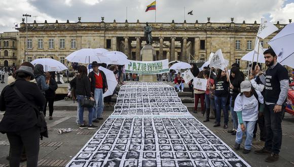 Las imágenes de personas desaparecidas y víctimas del conflicto armado se muestran durante una protesta frente al teatro Colón en Bogotá, mientras los miembros del gobierno colombiano y las FARC asisten a una ceremonia para conmemorar el primer aniversario del acuerdo de paz el 24 de noviembre de 2017.(Foto: AFP).