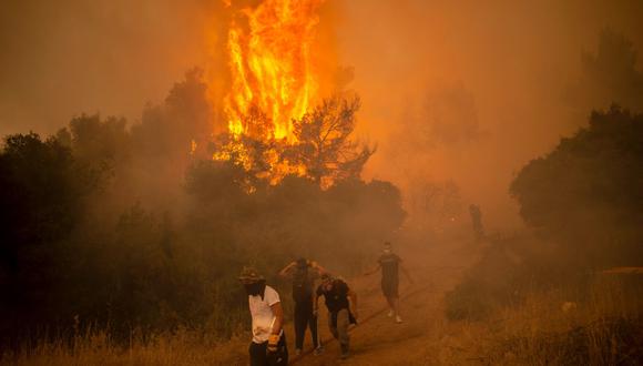 Los bomberos y voluntarios intentan extinguir un incendio en la aldea de Villa, en el noroeste de Atenas, Grecia, el 18 de agosto de 2021. (ANGELOS TZORTZINIS / AFP).