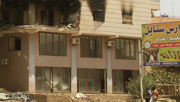 Hombres pasan frente a un edificio dañado durante las batallas entre las fuerzas de dos generales sudaneses rivales en la parte sur de Jartum, el 23 de abril de 2023. (Foto de AFP)