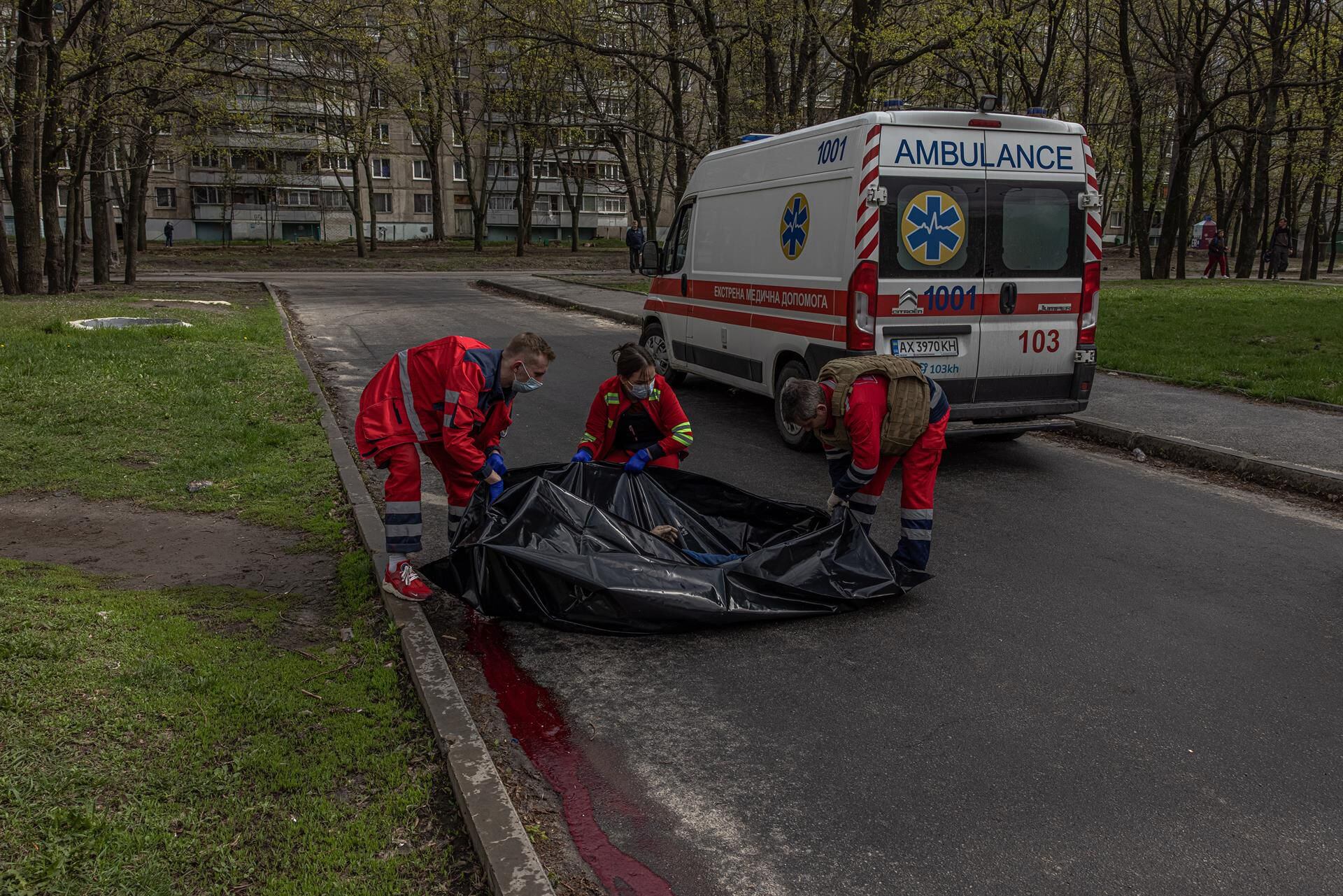 Medics place the body of a dead civilian in a body bag in the residential area that was hit by Russian artillery shelling in Kharkiv, northeastern Ukraine, on April 19, 2022. (EFE/EPA/ROMAN PILIPEY).