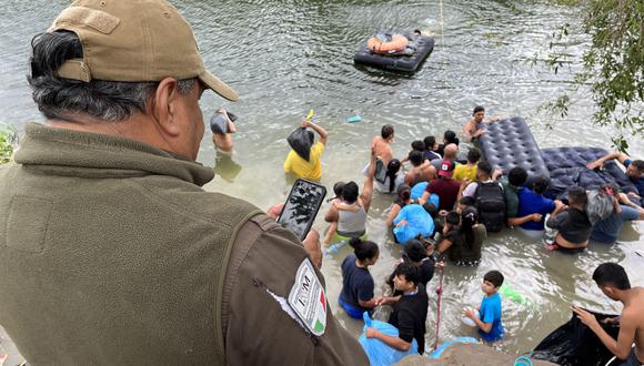 Un integrante del Instituto Nacional de Migración (INM) observa a un grupo de migrantes que intentan cruzar el Río Bravo, el 24 de abril de 2023, en la ciudad de Matamoros en Tamaulipas, México. (Foto de Abrahan Pineda-Jacome / EFE)