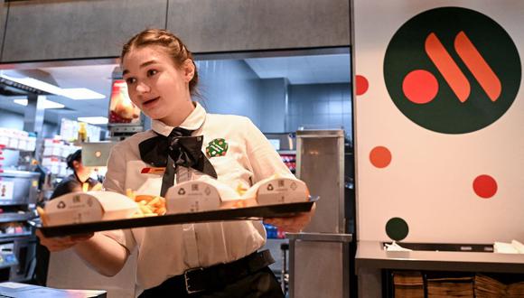 Una empleada sostiene un pedido de comida en una bandeja en la versión rusa de un antiguo restaurante McDonald's después de la ceremonia de apertura en Moscú el 12 de junio de 2022. (KIRILL KUDRYAVTSEV / AFP).