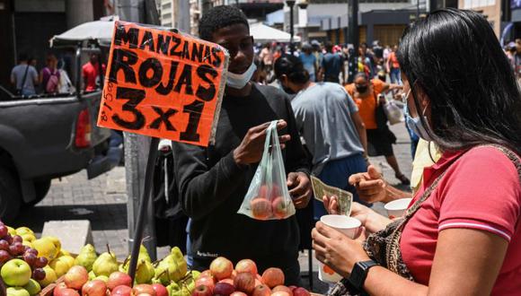 Una mujer compra manzanas en un puesto callejero con precios en dólares estadounidenses en el marco de la nueva conversión de moneda en Caracas. (Foto: Yuri CORTEZ / AFP).