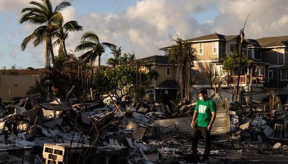 Un voluntario de Mercy Worldwide evalúa los daños de un complejo de apartamentos calcinados después de un incendio forestal en Lahaina, en el oeste de Maui, Hawái, el 12 de agosto de 2023. (Foto de Yuki IWAMURA / AFP)