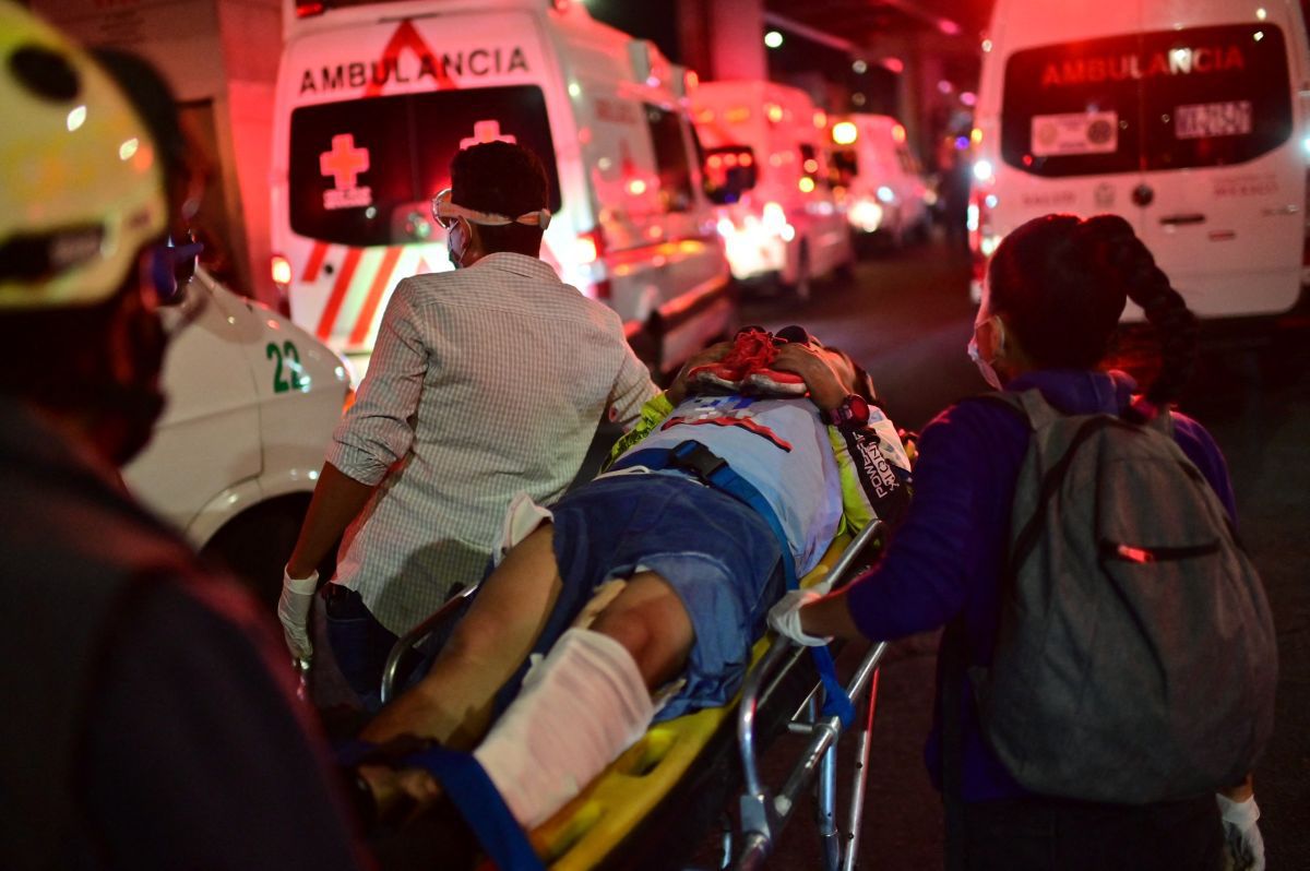 Emergency workers carry an injured person on a stretcher after a one-meter overpass partially collapsed in Mexico City. (Photo by Pedro PARDO / AFP).