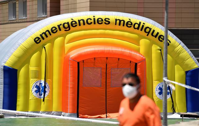 Un hombre con una máscara facial pasa por un hospital de campaña establecido para casos de coronavirus fuera del Hospital Universitario Arnau de Vilanova en Lleida, España. La región de Cataluña cerró un área con alrededor de 200.000 residentes por un rebrote de Covid-19. (Foto por Pau BARRENA / AFP).