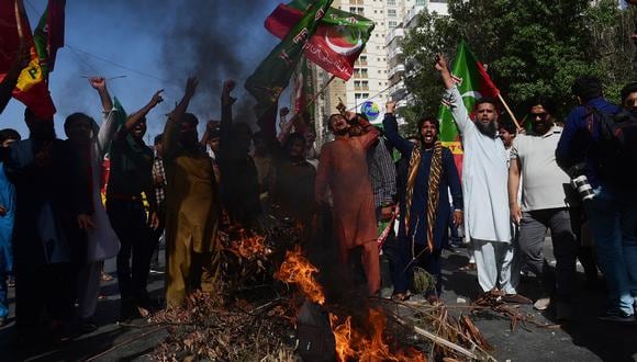 Activistas del partido Pakistan Tehreek-e-Insaf y simpatizantes del ex primer ministro de Pakistán, Imran Khan, gritan junto a un incendio durante una protesta contra el arresto de su líder en Karachi el 9 de mayo de 2023. (Foto de Asif HASSAN / AFP)