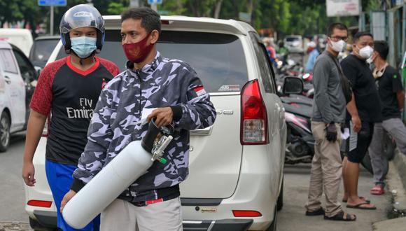 Un hombre lleva tanques de oxígeno para familiares enfermos de coronavirus en Yakarta, Indonesia, el 30 de junio de 2021. (Foto de BAY ISMOYO / AFP).
