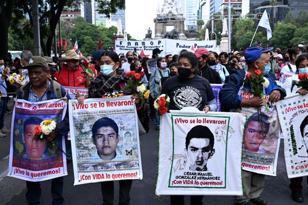 Personas portan carteles de los estudiantes desaparecidos durante una marcha en la Ciudad de México el 26 de septiembre de 2022. (Foto de Rodrigo ARANGUA/AFP).