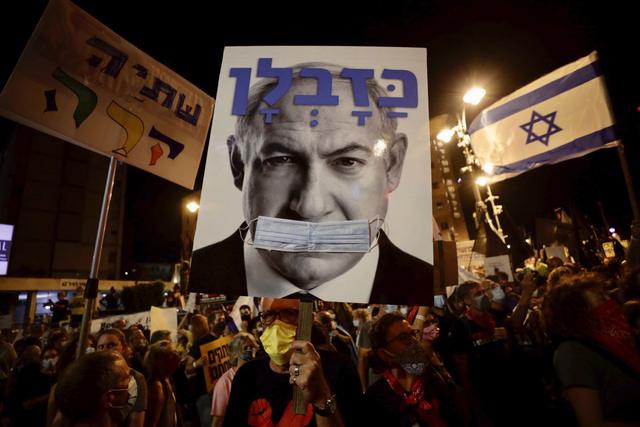 Manifestantes israelíes sostienen carteles durante una manifestación contra el primer ministro israelí, Benjamin Netanyahu, frente a la residencia del primer ministro en Jerusalén. (AP/Sebastian Scheiner).