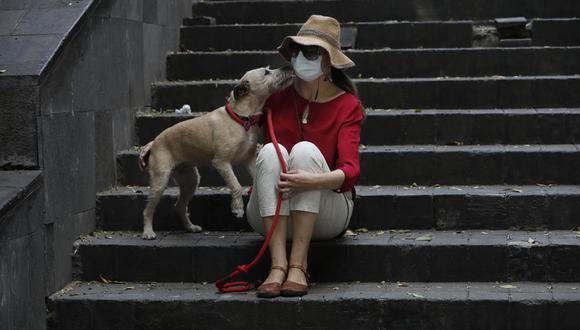 Una mujer, con mascarilla para evitar el contagio de coronavirus, acompañada de su perro durante una visita al parque, el jueves 16 de abril de 2020, en la Ciudad de México. (AP Foto/Marco Ugarte).