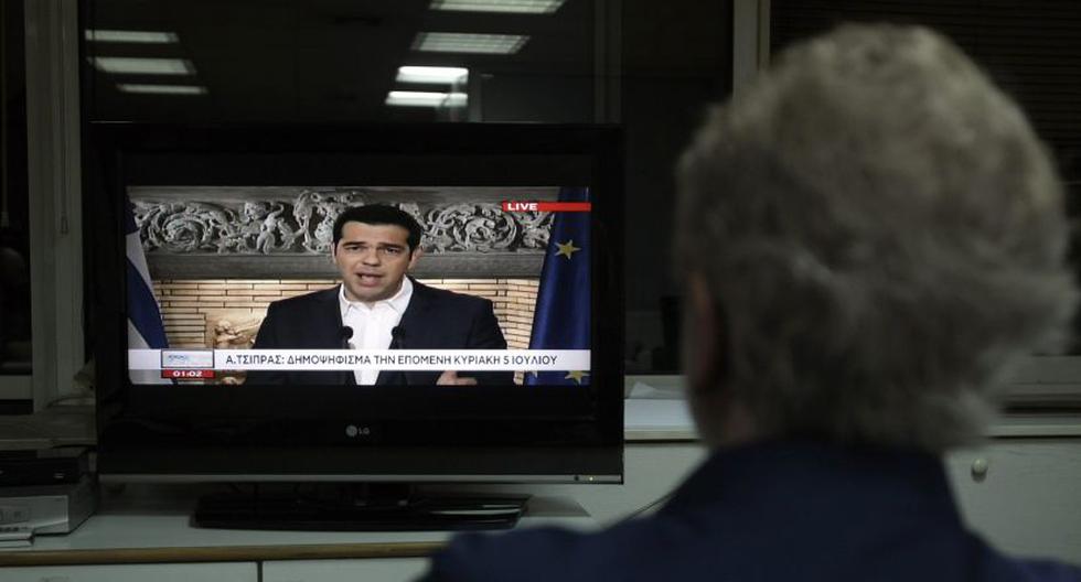 Un hombre mira a Tsipras anunciando el referéndum en la TV. (Foto: EFE)