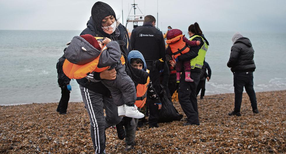 Una migrante lleva a sus hijos tras desembarcar de un bote salvavidas en una playa de Dungeness, en la costa sureste de Inglaterra. Fue rescatada mientras cruzaba el Canal de la Mancha. (Foto: AFP)