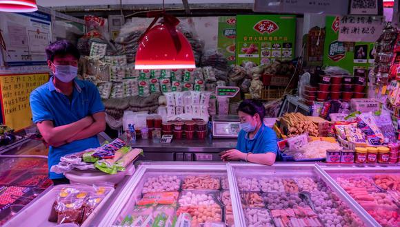 Los vendedores esperan a los clientes en su puesto de venta de carne congelada y mariscos en un mercado en Beijing el 20 de junio de 2020. (Foto de NICOLAS ASFOURI / AFP).