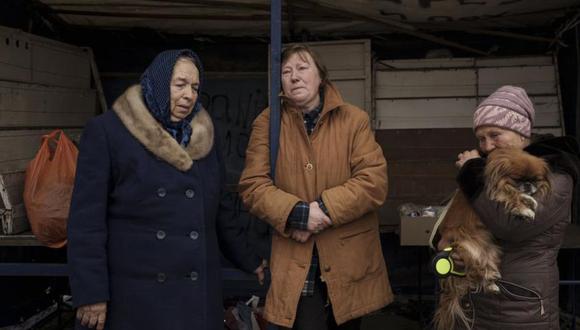 Tres personas que huyeron de la aldea de Ruska Lozova esperan en un puesto de control en Járkiv, Ucrania.