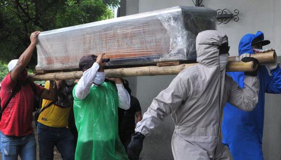 Los familiares de una persona que murió por el nuevo coronavirus, algunos con trajes protectores, llevan el ataúd envuelto dentro de un cementerio en el norte de Guayaquil, Ecuador. (Foto: AFP / Jose Sanchez LINDAO).