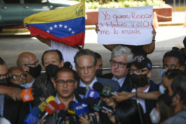 A woman holds the message in Spanish "I want to recall Maduro and the CNE is blocking me" behind Nicmer Evans, who represents a referendum movement to recall President Nicolás Maduro, speaking to the press in front of the National Electoral Council (CNE) in Caracas Venezuela.  (Photo: AP/Matias Delacroix)
