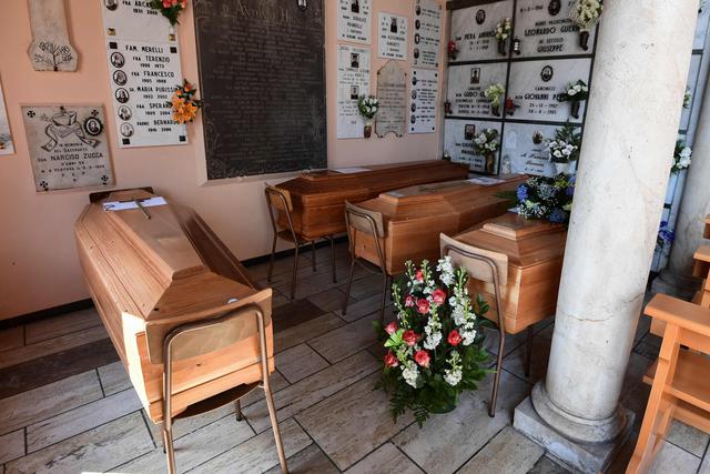 Una fotografía tomada el 23 de marzo de 2020 muestra ataúdes que esperan ser incinerados en la entrada de la capilla del cementerio en el pequeño pueblo de Vertova, cerca de Bérgamo, Lombardía, donde 50 personas murieron de coronavirus. (AFP / MIGUEL MEDINA).
