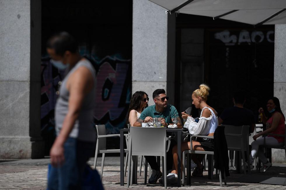 Las personas comparten bebidas y alimentos en un bar con terraza en la Plaza Mayor de Madrid esta mañana tras el inicio de desconfinamiento en la capital de España, país que fue seriamente afectado por la pandemia de coronavirus. (PIERRE-PHILIPPE MARCOU / AFP).