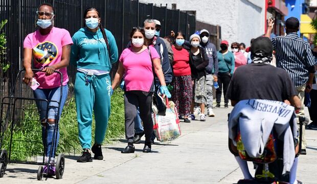 La gente usa su máscara facial esperando en fila para una distribución de alimentos de emergencia en Los Ángeles, California, durante la pandemia de coronavirus. (Foto: AFP/Frederic J. Brown)