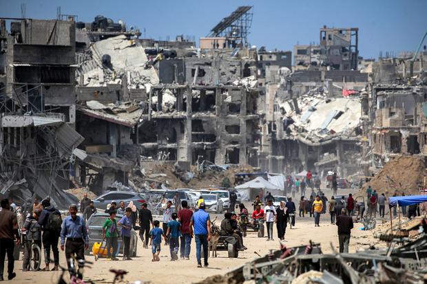 La gente pasa junto a edificios destruidos a lo largo de una calle en Khan Yunis, en el sur de la Franja de Gaza, el 14 de mayo de 2024, en medio del conflicto en curso en el territorio palestino entre Israel y Hamás. (Foto de AFP).