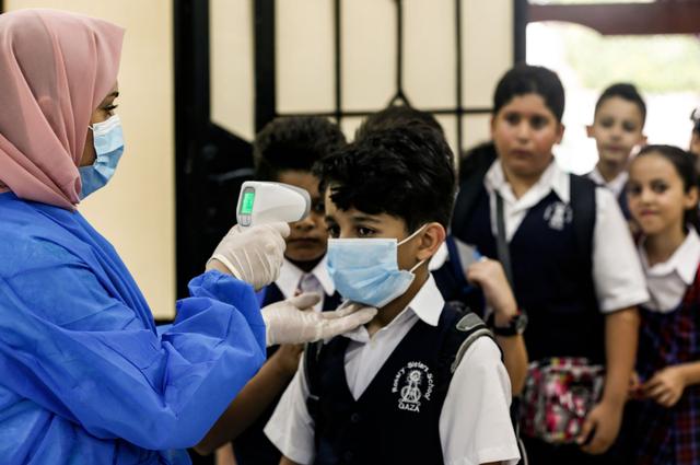 Un miembro del personal de la escuela Rosary Sisters en la ciudad de Gaza verifica la temperatura de los estudiantes que regresan a clases tras las medidas impuestas por el coronavirus. (AFP / MAHMUD HAMS).