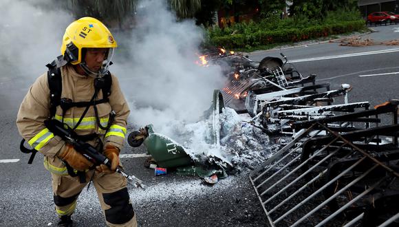 Un bombero chino controla las llamas desatadas durante una protesta. (Foto Referencial: Reuters)