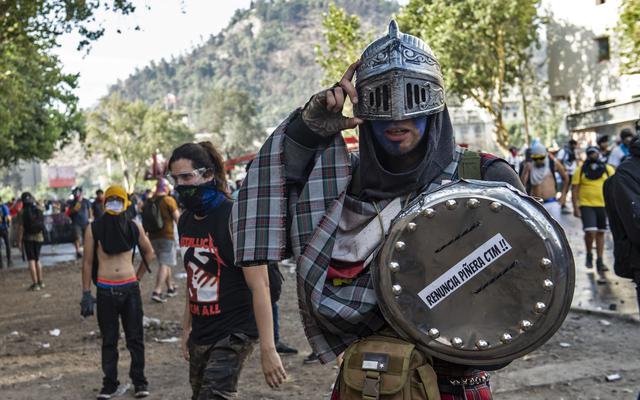 "Los valientes" (para unos), "los cobardes" (para otros) pican la calle para sacar pavimento, destruyen paradas de buses para obtener varas de metal y portan botellas para hacerlas volar hasta que exploten cerca de un uniformado. Si eso pasa gritan y aplauden. (Photo by Martin BERNETTI / AFP).
