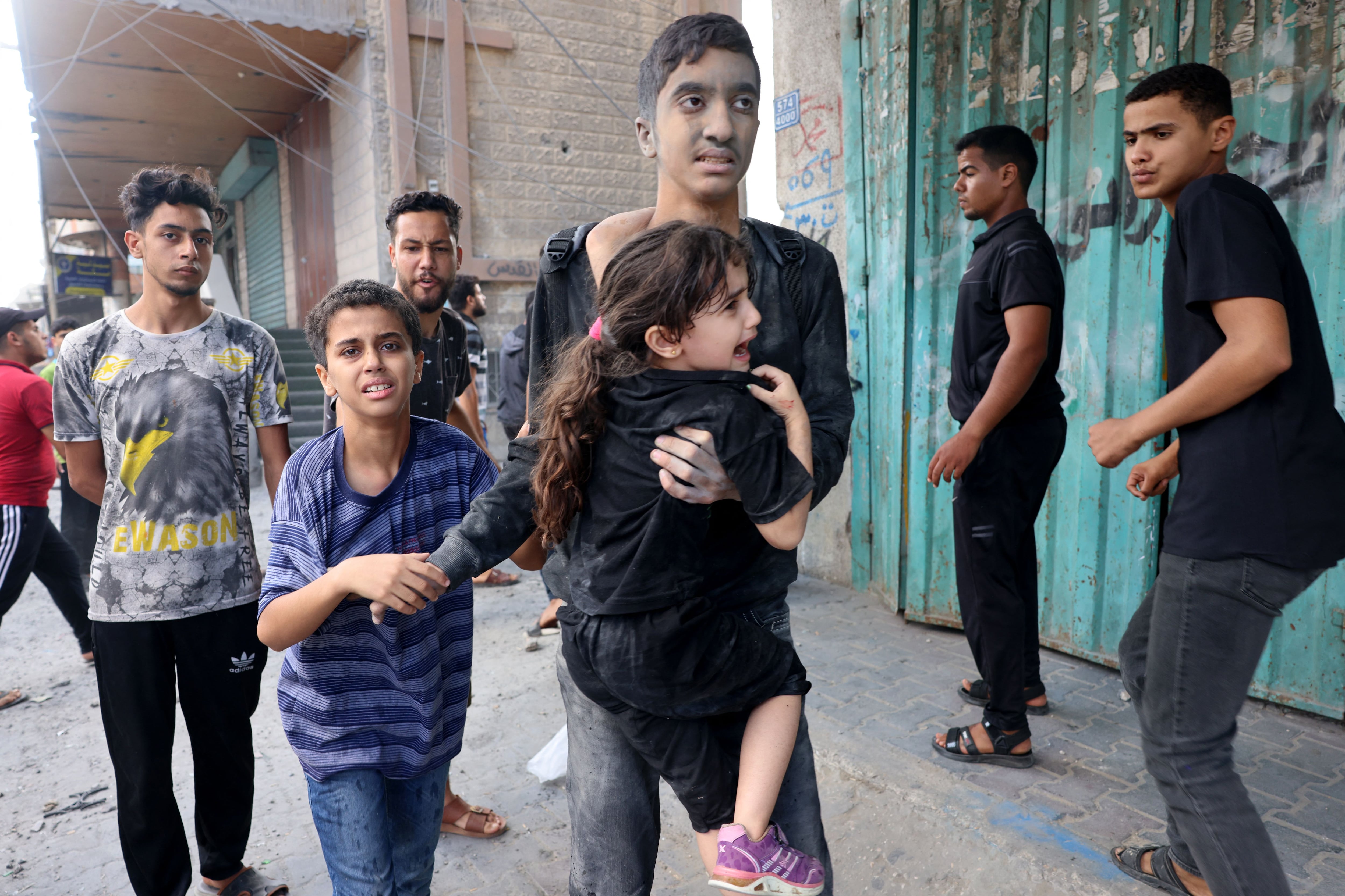 A young man carries a girl after an Israeli attack, as battles between Israel and the Hamas movement continue for the sixth consecutive day in Rafah, in the south of the Gaza Strip.  (Photo by SAID KHATIB/AFP).