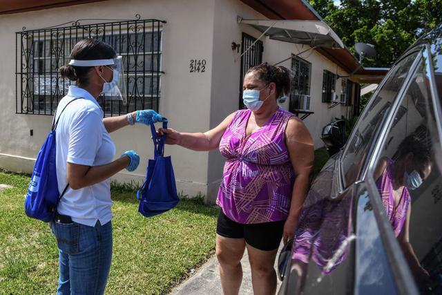 Casa por casa, un grupo de trabajadores reparte mascarillas y sanitizadores en Miami, intentando convencer a los vecinos de que los usen en un esfuerzo de hormiga para combatir el mastodóntico avance del coronavirus en Florida. (AFP /CHANDAN KHANNA).