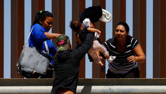 Un migrante que busca asilo entrega a un niño por encima de la barandilla mientras salen del río Bravo después de cruzarlo, en El Paso, Texas, EE.UU., visto desde Ciudad Juárez, México, el 6 de abril de 2022.