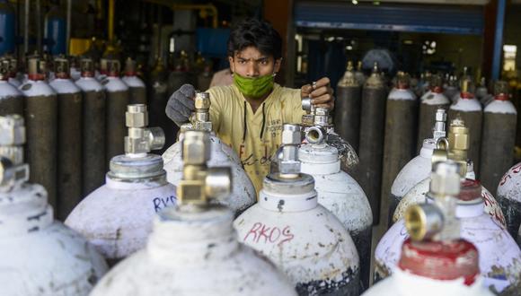 Un trabajador organiza cilindros de oxígeno médico para transportarlos a los hospitales, para el tratamiento del coronavirus, en una instalación en las afueras de Hyderabad, India. (Foto: Noah Seelam/ AFP).