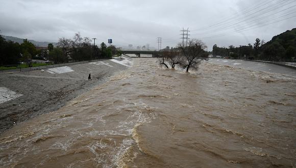 Una persona camina hasta el borde del embravecido río Los Ángeles mientras la segunda y más poderosa de dos tormentas fluviales atmosféricas inunda Los Ángeles, California, el 5 de febrero de 2024. (Foto de Robyn Beck / AFP)
