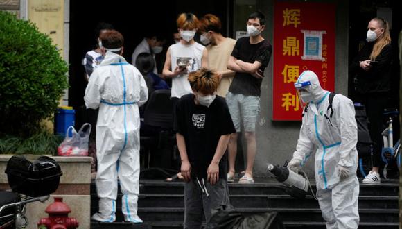 Un trabajador con traje protector desinfecta a una persona durante el encierro, en medio del brote de la enfermedad por coronavirus (COVID-19), en Shanghái, China.