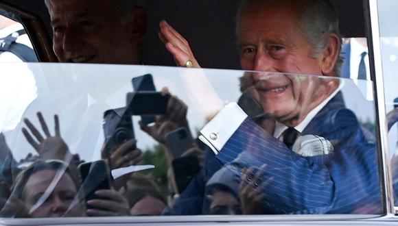 El rey Carlos III de Gran Bretaña saluda a los miembros del público que esperan cuando llega en automóvil al Palacio de Buckingham en Londres el 11 de septiembre de 2022. (Foto de Alain JOCARD / AFP)