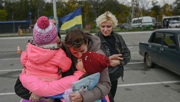 Una mujer ucraniana (segunda a la izquierda) y sus hijos son recibidos por un pariente después de que pudieron salir del territorio ocupado por Rusia de Kherson, en Zaporizhzhia, el 21 de octubre de 2022, en medio de la invasión de Rusia a Ucrania (Foto: BULENT KILIC / AFP / Referencial)