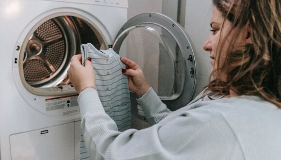 Una mujer metiendo la ropa de su bebé a la lavadora. | Imagen referencial: Pexels