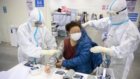El personal médico que usa trajes protectores atiende a una paciente en un hospital provisional de Wuhan, el epicentro del coronavirus. (EFE).
