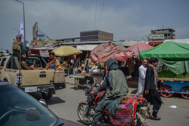 Combatientes talibanes en una camioneta pick-up (izquierda) se mueven alrededor de un área de mercado en Kote Sangi, Kabul (Afganistán), el 17 de agosto de 2021, (Hoshang Hashimi / AFP).
