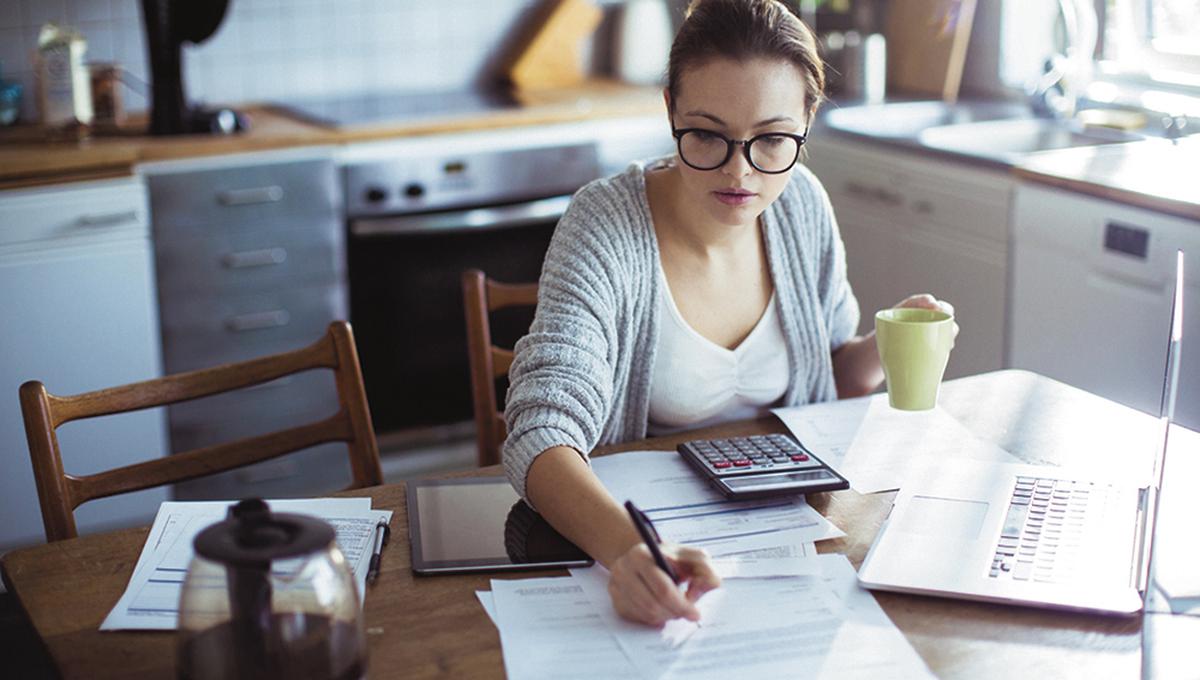 Close up of a young woman doing her bills in the kitchen